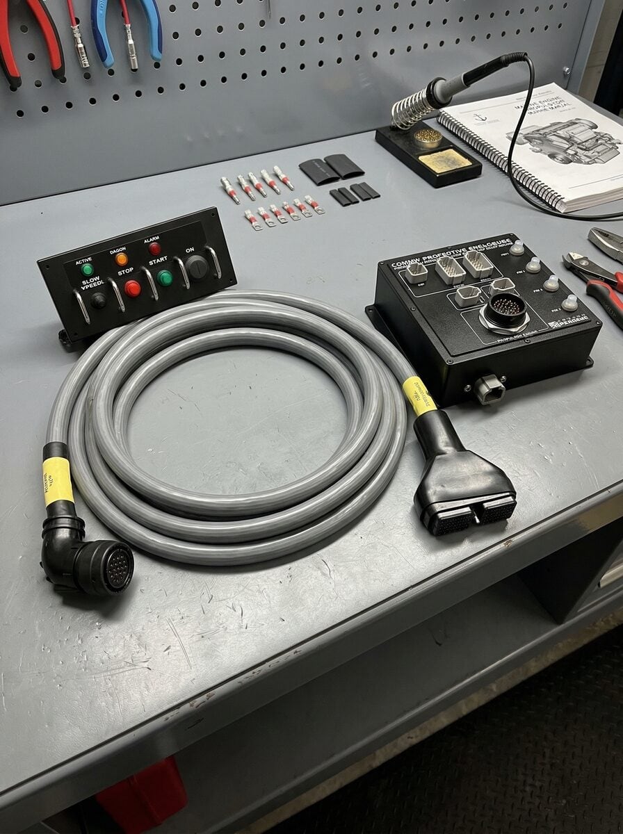 Engine wiring harness with a start/stop station panel and engine interface enclosure on the workbench